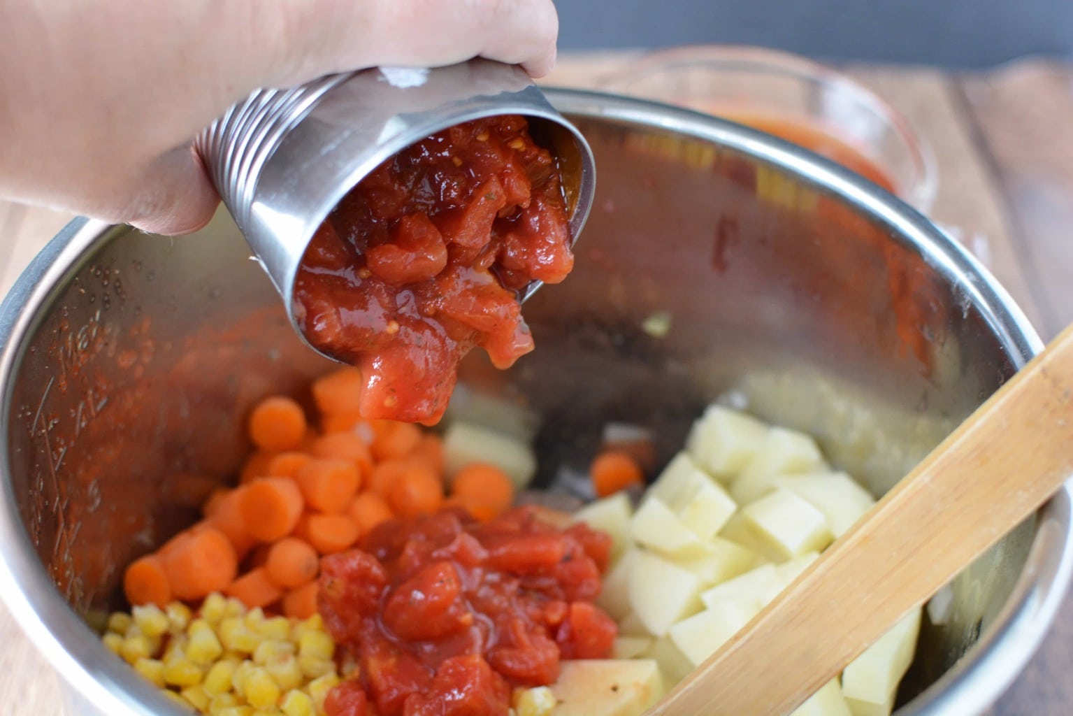 pouring can of tomatoes into pot