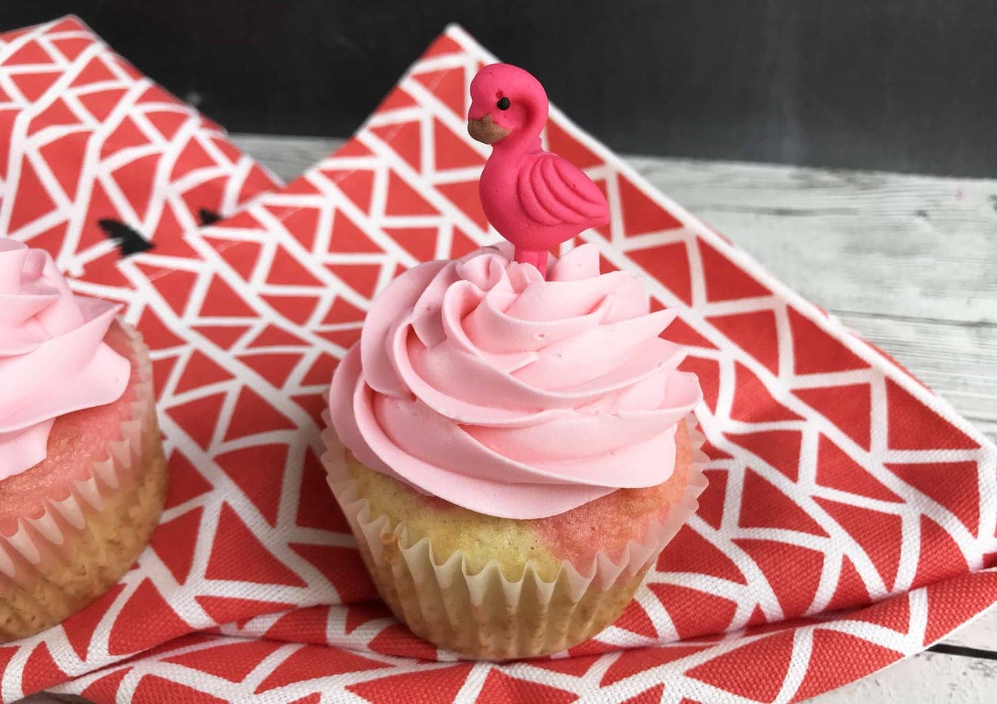 flamingo cupcakes with pink icing and a flamingo candy on top