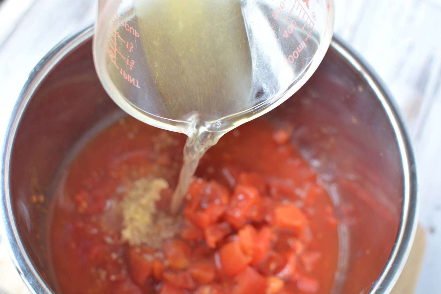 pouring broth onto tomatoes in pot