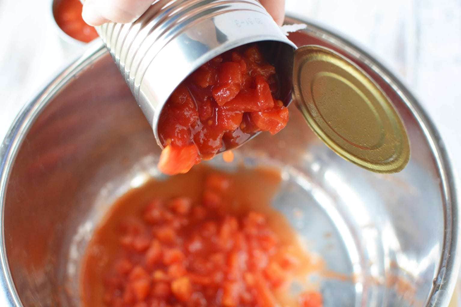 pouring can of tomatoes into pot