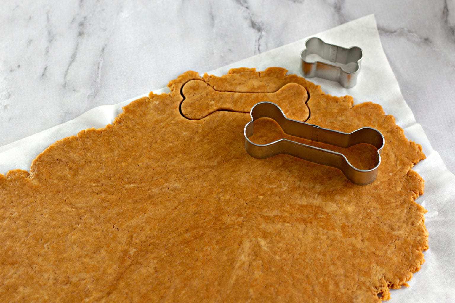 using dog bone cookie butter to cut out dough