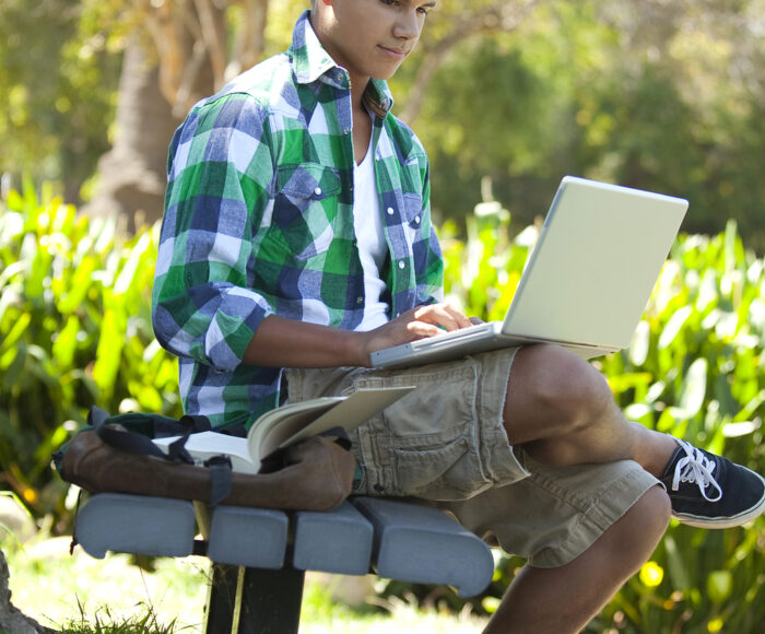 Teen student studying with backpack studying outside