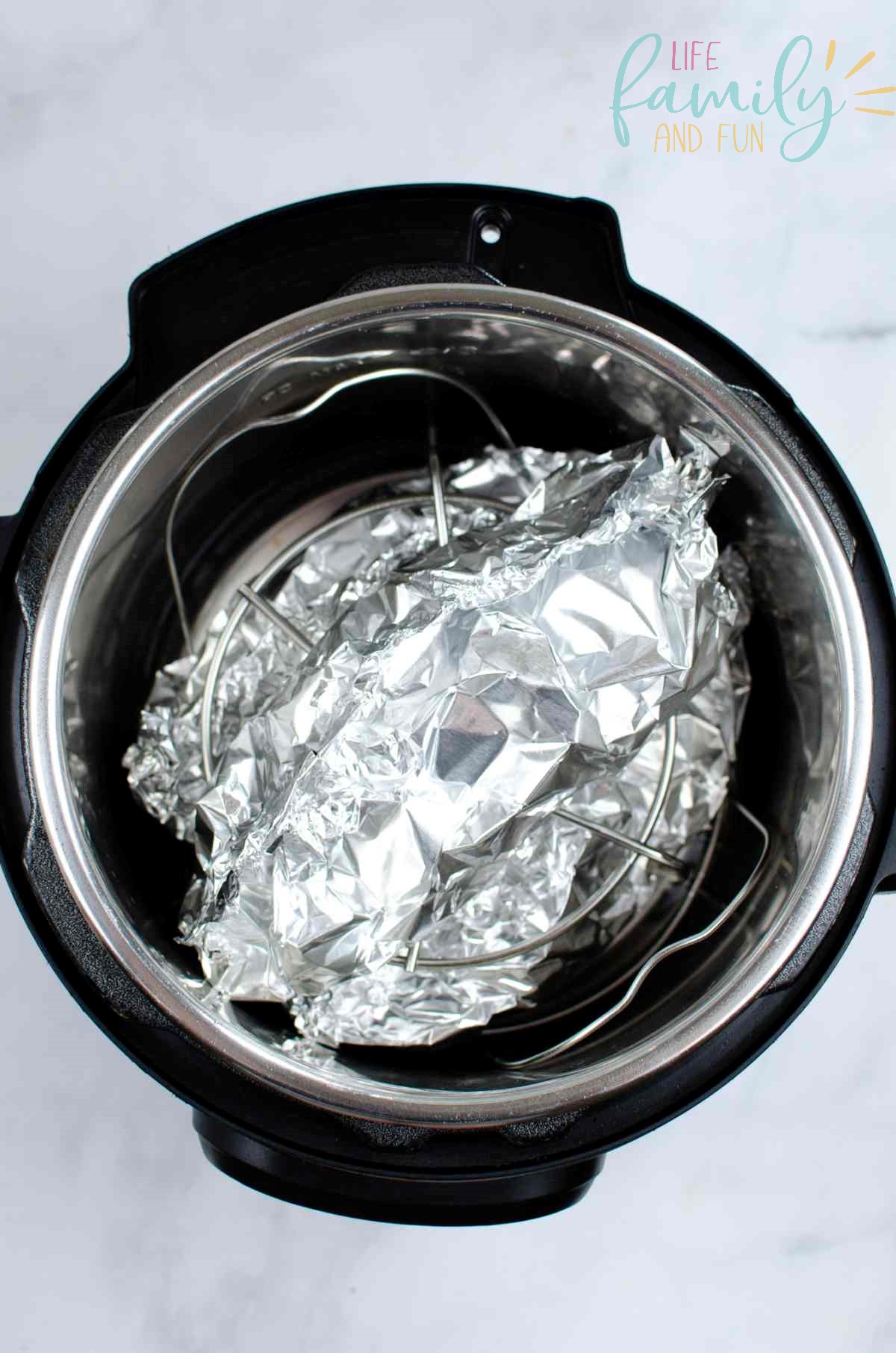 chicken wrapped in foil on trivet in instant pot