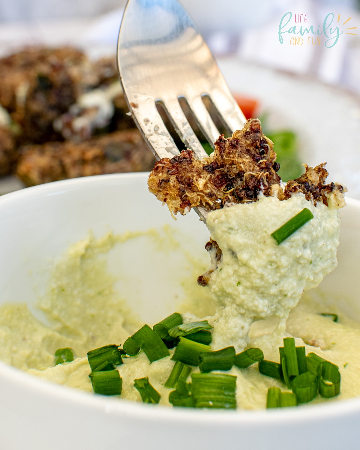 piece of quinoa cake on fork being dipped in cashew sauce 