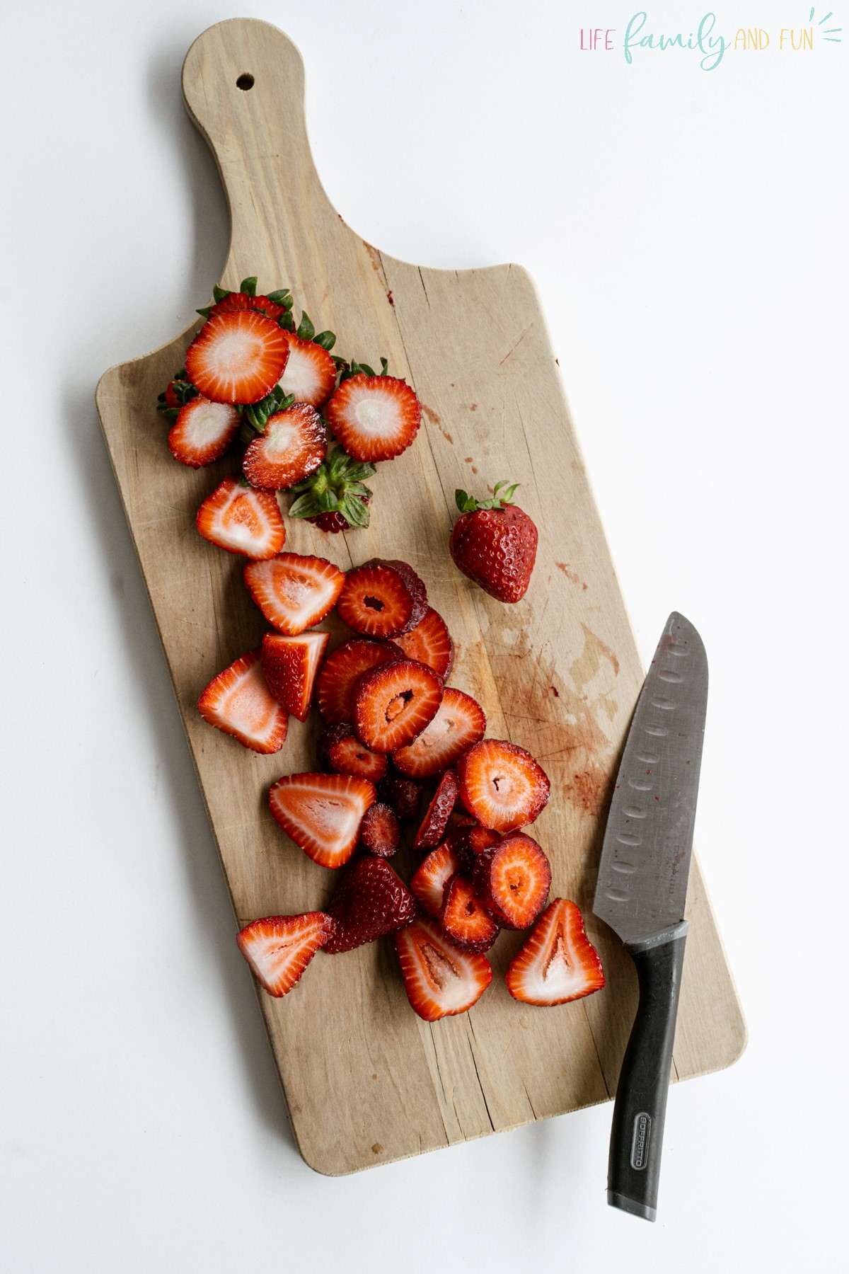 cutting strawberries on board with knife
